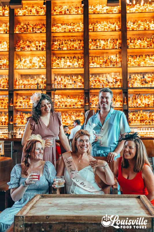 Bachelorette party in front of bourbon wall at the Last Refuge in NuLu, Louisville KY