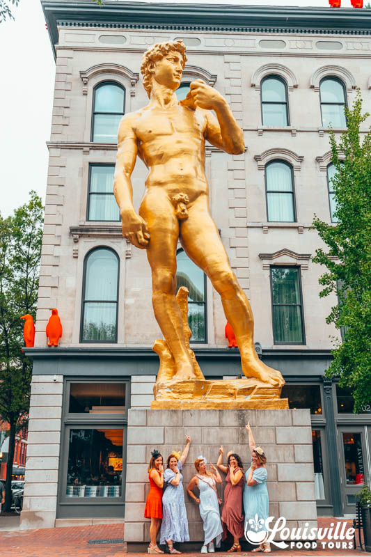 Bachelorette Party posing with the statue of David in downtown Louisville Kentucky on a tour with Louisville Food Tours